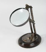 AN ADJUSTABLE MAGNIFYING GLASS on wooden base. 5ins diameter.