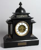 A VICTORIAN BLACK MARBLE FRENCH STRIKING MANTLE CLOCK with four columns, 15ins high, presented by