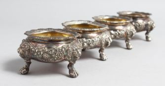 A SET OF FOUR VICTORIAN CASTE SILVER CIRCULAT SALTS with lion masks, claw and ball feet,3ins