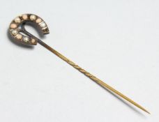 A GOLD AND PEARL HORSE SHOE SHAPE STICK PIN.