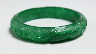 A CHINESE CARVED APPLE GREEN JADE BANGLE.