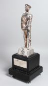 A WHITE METAL FIGURE OF A STANDING SOLDIER wearing his medals with badge. 12ins high, on a square