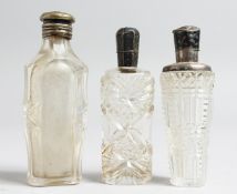 THREE SILVER TOPPED CUT GLASS SCENT BOTTLES.