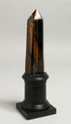 A GOOD TIGER'S EYE OBELISK, 5ins high. on a wooden base