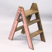 A PAIR OF FOLDING PINE STEPS, painted to the sides with champagne makers on a pink background
