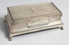 AN ENGINE TURNED SILVER RECTANGULAR CIGARETTE BOX on four claw feet, 8ins long, cedarwood liner,