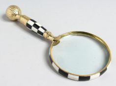 A MAGNIFYING GLASS with BRASS AND CHEQUERED handle.
