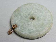 A CHINESE CIRCULAR JADE PENDANT with gold mounts, 2.25ins diameter.