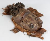 AN AFRICAN CARVED WOOD MASK the head with nails and feathers. 13ins long.