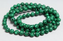 A STRING OF MALACHITE BEADS, 33ins long.
