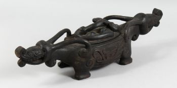 A BORNEO CARVED WOOD ZOOMORPHIC LIDDED FOOD BOWL, carved to each end with mythological beasts. 2ft