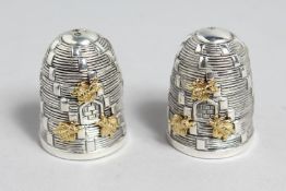 A PAIR OF 800 WHITE METAL BEE HIVES SALTS AND PEPPERS.