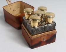 AN ART DECO LEATHER CASED SET OF FIVE GLASS PERFUME BOTTLES with gilt metal tops.