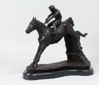 A GOOD BRONZE OF A HORSE AND JOCKEY JUMPING OVER A HEDGE. 14ins long.
