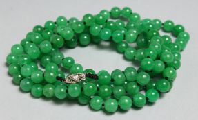A STRING OF JADE BEADS WITH GOLD AND DIAMOND CLASP, 46ins long.