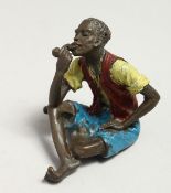 A PAINTED BRONZE COLD CAST SEATED MAN SMOKING A PIPE, 5cm.