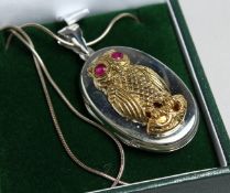A SILVER OWL LOCKET with ruby eyes and chain.