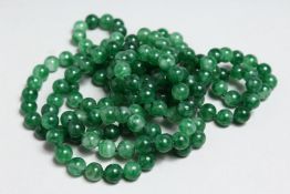 A LONG STRING OF DARK GREEN JADE BEADS, 50ins long.