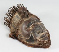 AN AFRICAN CARVED WOOD MASK the head with a scull and nails. 14ins long.