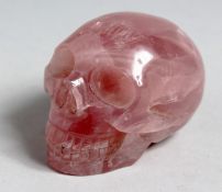 A SMALL CARVED ROSE QUARTZ SKULL, 3ins long.