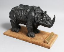 A BRONZED RHINOCEROS on a wooden base, 13ins long