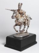 A WHITE METAL GROUP OF A SOLDIER ON HORSEBACK charging to the enemy. 11.5ins high, on a