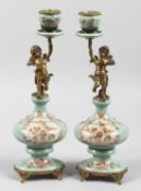 A PAIR OF PORCELAIN AND ORMOLU CHERUB CANDLESTICKS. 14ins high.