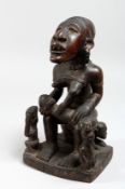 A GOOD CARVED WOOD AFRICAN FIGURE GROUP, a mother seated with a child on her lap. 11.5ins high.