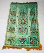 A SILK SUZANI TEXTILE, green ground embroidered with floral motifs and verses of the quran in