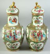 A PAIR OF CHINESE CANTON FAMILLE ROSE PORCELAIN VASES AND COVERS, painted with panels of figures