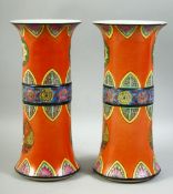 A RARE PAIR OF CHINESE ORANGE GROUND PORCELAIN GU VASES, decorated with various motifs, each with