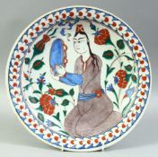 A TURKISH OTTOMAN IZNIK PLATE, decorated with a figure and flora, 31.5cm diameter.