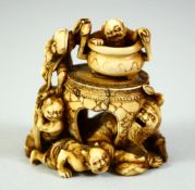 A JAPANESE CARVED IVORY NETSUKE, depicting a man crouching beneath a table with a cauldron on the