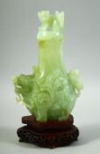 A CHINESE CARVED JADE VASE AND COVER on a fitted hardwood stand, the vase carved with foo dogs,