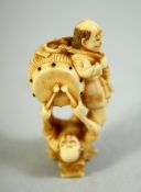 A JAPANESE CARVED IVORY NETSUKE, of a standing male figure with a drum upon his back, a figure