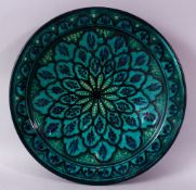 A 20TH CENTURY IZNIK POTTERY CIRCULAR BOWL, green ground painted with flower head design, 39cm