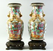 A GOOD PAIR OF CHINESE CANTON PORCELAIN VASES mounted to brass stands, the body of each painted with