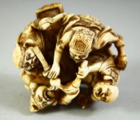 A JAPANESE CARVED IVORY NETSUKE, carved as four figures in a circle holding brushes, with red seal