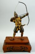 A JAPANESE GILDED BRONZE OKIMONO of a samurai archer, his bow and arrow drawn, mounted to a carved