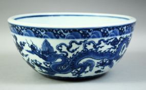 A LARGE CHINESE BLUE AND WHITE PORCELAIN BOWL, decorated with dragons amongst stylised clouds, the
