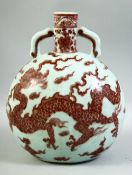 A CHINESE RED UNDERGLAZE PORCELAIN TWIN HANDLE MOONFLASK, decorated with a dragon amongst stylised