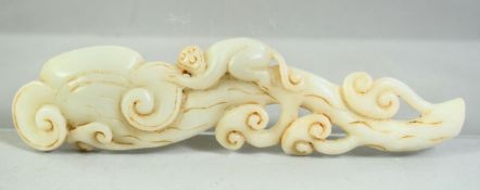 A CHINESE CARVED JADE MODEL OF A MONKEY UPON A RUYI FORMED BRANCH, 15cm long.