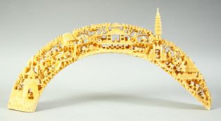 A CHINESE CARVED AND PIERCED IVORY TUSK BRIDGE, carved with many figures carrying out various