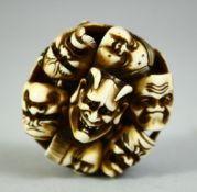 A JAPANESE CARVED IVORY NETSUKE, carved as a roundel of noh masks, signed, 4.5cm.