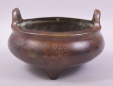 A CHINESE BRONZE TWIN HANDLE TRIPOD CENSER, with four character mark to base, 15cm diameter.
