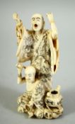 A JAPANESE CARVED IVORY OKIMONO GROUP, depicting a standing priest with another priest at his