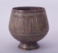 A FINE ISLAMIC SILVER INLAID BRASS GOBLET, decorated with a band of calligraphy, 8.5cm high.