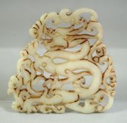 A CHINESE CARVED AND PIERCED AMULET DEPICTING A DRAGON, 8cm x 8cm.