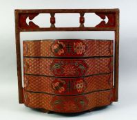 A CHINESE RED LACQUER FOUR TIER STACKING BOX with handle, the cases decorated with auspicious
