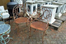 A pair of wrought iron garden armchairs.